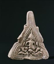 A roof finial with a worn image of a Bodhisattva