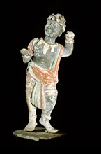 An unglazed and painted pottery model of a curly headed and bejewelled youth probably from Western Central Asia
