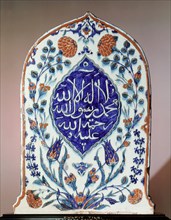 A tombstone shaped tile, possibly made for a mausoleum, bearing the creed there is no God but God; Muhammad is his prophet; may God show mercy to him