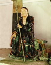 A statue of an arhat, sitting with a staff in his left hand
