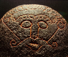 Detail of a forge stone incised with the face of the god Loki with lips sewn together