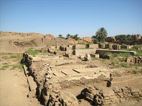 Ruins of a Ptolemaic building in the foreground with the mud-brick enclosure wall in the background