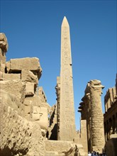 The obelisk raised by Tuthmosis II with the Great Hypostyle Hall in the background and a carved "ankh" symbol in the foreground