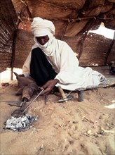 A blacksmith, possibly Tuareg or Songhay, forging iron