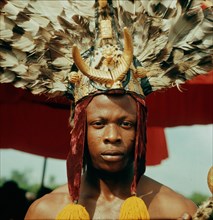 An attendant of the Omanhene of Akrokerri wearing elaborate feather headdress in the procession to celebrate the Yam Festival