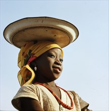 A Yoruba girl carrying her small stock of trade goods on her head