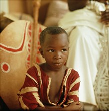 A Benin chief's son leaning against the shield of his father