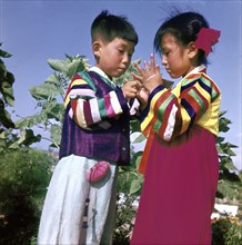 Two young Korean children in traditional dress playing Cat's Cradle