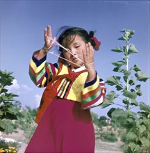 A young Korean girl in traditional dress playing Cat's Cradle