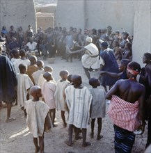 A crowd watches music and dancing in front of the deceased's house at a Dogon funeral ceremony
