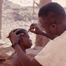 A Dogon woman having her hair dressed