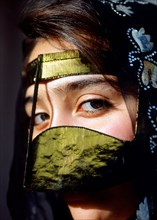 Young woman wearing a gilded burqa or face mask