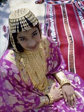 Young woman wearing silver bridal headdress and gold jewellery