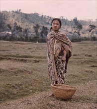 A girl wearing batik garments, underneath which she carries a baby