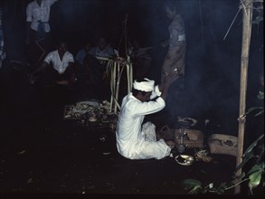 A pemangku, priest, prays for blessings before offerings to the spirits