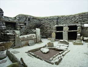 View of the rectangular central hearth and the massive stone built version of the old "farmhouse dresser", situated opposite the entrance of the House 1