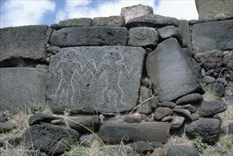 Petroglyphs of two men carved on stone slab, forming part of the foundations for the re-erected Moai platform at Anakena Bay