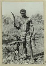 Aboriginal man and a child holding boomerangs