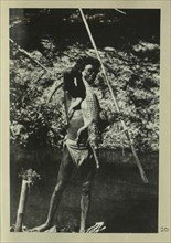 Aboriginal man holding a crocodile and spears