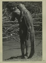 Aboriginal man holding crocodiles on his back