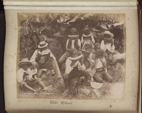 Eight boys in a field eating water melons