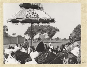 Side view of Emir on horseback and under ceremonial umbrella