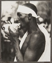 Side view of a man blowing a conch