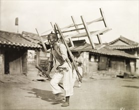 A Korean labourer carries a bench