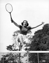 Woman Player Leaping Over Net