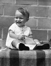 A Laughing Baby With A Book