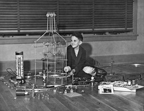 A young boy playing with his Electric Tinker Toy set with a model train runnning through the middle of the setup.