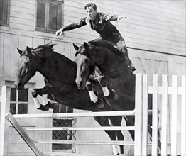 A Stunt Rider On Two Horses.
