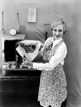 United States:  c. 1923.
A woman trims the excess crust off a pie before baking.