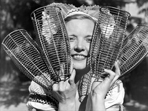 California:  c. 1934.
A woman holding up the baskets that will dress the California champagne