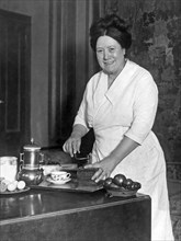 United States:  c. 1925.
A woman in a home preparing to serve coffee.