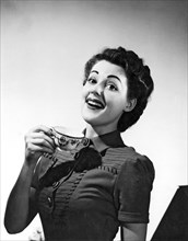 A perky woman enjoys her cup of coffee.