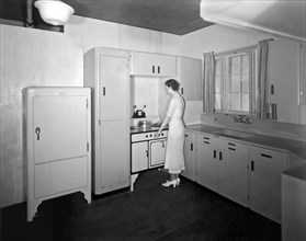 Beaver Dam, Wisconsin  c. 1932.
A woman cooking in her sparsely furnished kitchen.