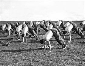 A group of men doing calisthetics on an athletic field