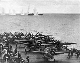 Japanese salvos drop next to the USS White Plains as the USS Kitkun Bay scrambles its fighters during the 2nd Battle of the Philippine Sea.