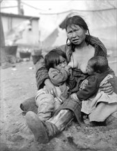 Alaska, United States:  1904.
An Inuit Eskimo woman breast-feeding two babies.