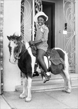 United States:  c. 1950.  
A very happy African American girl on a pony.