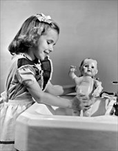 A young girl plays with her new all-vinyl plastic doll that can be washed without fear of damage.