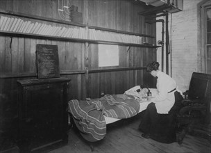 A patient. A sick worker receiving First Aid, in room set apart for hospital use and library. 1912