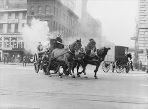 Team of Horses pulls a steam pumper across paved streets toward a fire scene.