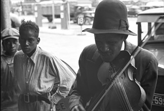 African American boy listen to a violin player 1939