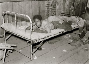 African American Boy resting on bed in attic of sharecropper shack. New Madrid County, Missouri 1938