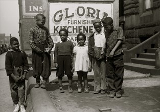 African American Children in front of a sign selling kitchenettes 1940