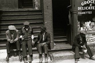 African American congregate on the steps next to a Delicatessen 1938