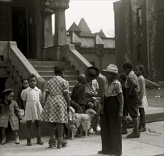 African American inner city children with Mother on stoop with dog 1940