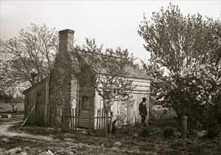 African American man in front of small house 1901